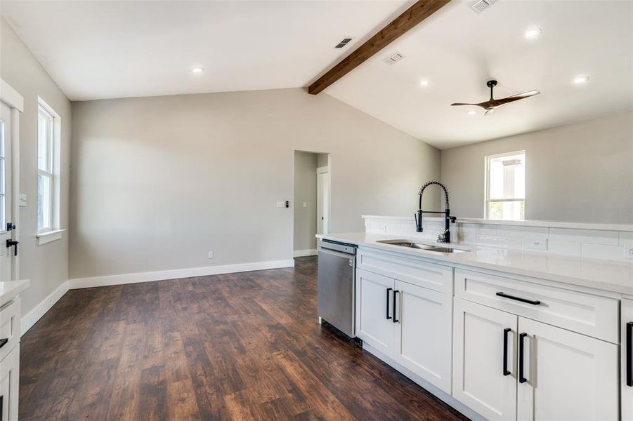 Kitchen featuring dishwasher, white cabinets, sink, ceiling fan, and a healthy amount of sunlight