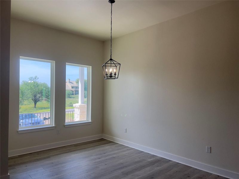 A refined pendant light casts a warm glow over sleek wood flooring in this versatile living space.