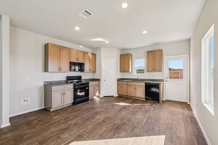 Image of a kitchen with brown cabinets, black appliance and a window above the sink
