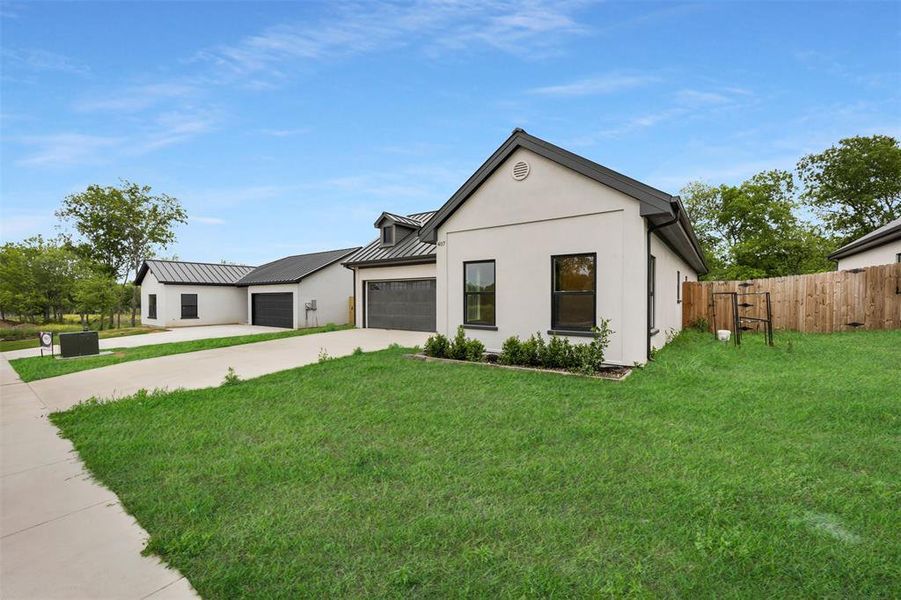 View of front of house featuring a standing seam roof, metal roof, a garage, fence, and driveway View of front of house featuring a standing seam roof, metal roof, a garage, fence, and driveway