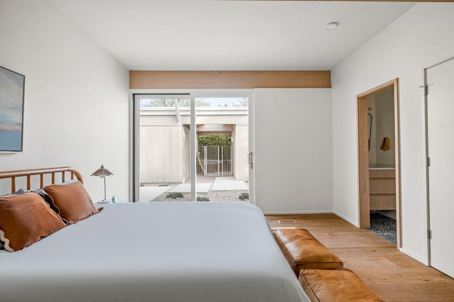 Bedroom featuring access to outside, light wood-type flooring, and connected bathroom