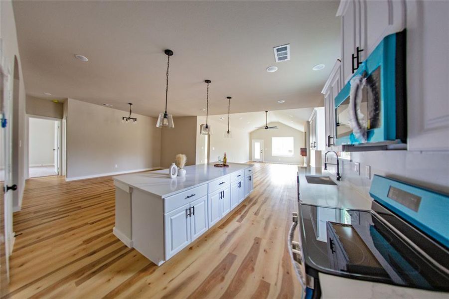 Kitchen with open floor plan, range with electric cooktop, lofted ceiling, white cabinetry, and recessed lighting