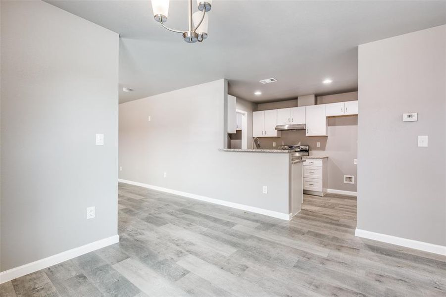 Kitchen with white cabinets, light hardwood / wood-style flooring, pendant lighting, and an inviting chandelier