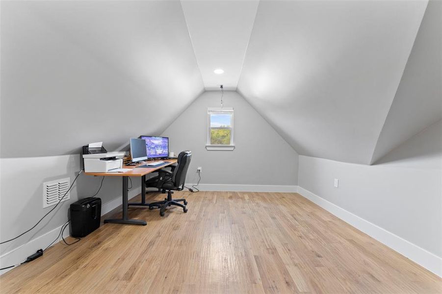 Home office with lofted ceiling and light wood-style flooring Home office with lofted ceiling and light wood-style flooring