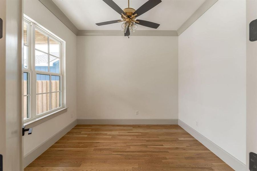 Empty room featuring light wood finished floors, ceiling fan, and crown molding