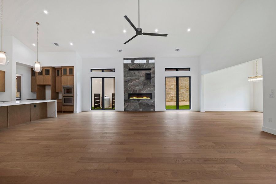 Spacious living area featuring wood-finish flooring, a contemporary ceiling fan, and recessed lighting