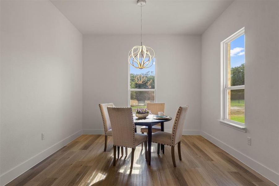 Dining room with healthy amount of natural light, light wood finished floors, and a chandelier