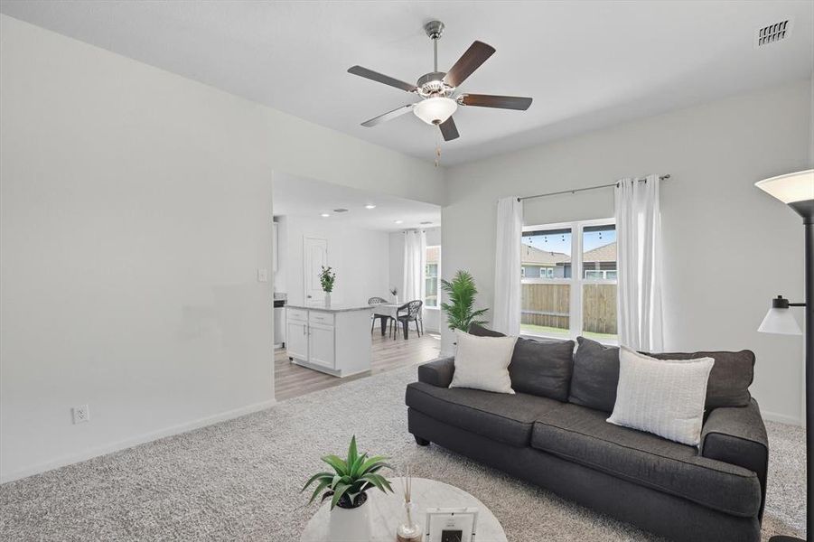 Living area with light colored carpet and a ceiling fan