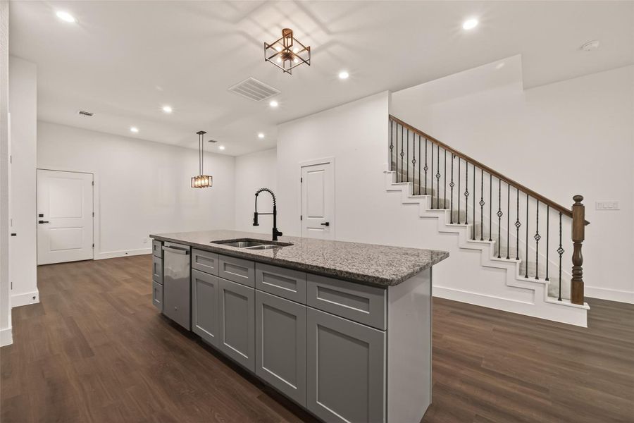 This modern home features an open-concept kitchen with a large island, granite countertops, and sleek cabinetry. It has a stylish staircase with decorative iron railing, recessed lighting, and wood flooring, providing a warm and inviting atmosphere. This modern home features an open-concept kitchen with a large island, granite countertops, and sleek cabinetry. It has a stylish staircase with decorative iron railing, recessed lighting, and wood flooring, providing a warm and inviting atmosphere.