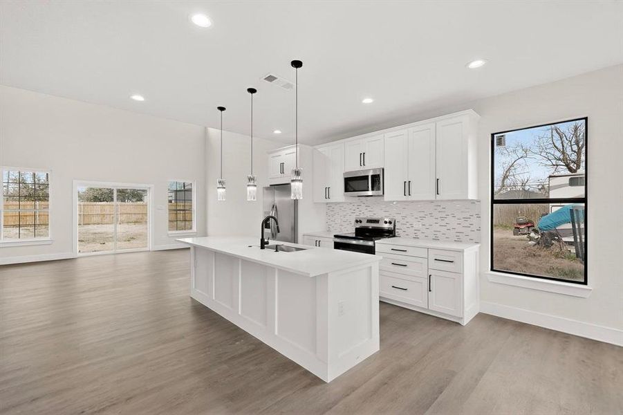 Kitchen featuring white cabinets, stainless steel appliances, plenty of natural light, and open floor plan Kitchen featuring white cabinets, stainless steel appliances, plenty of natural light, and open floor plan