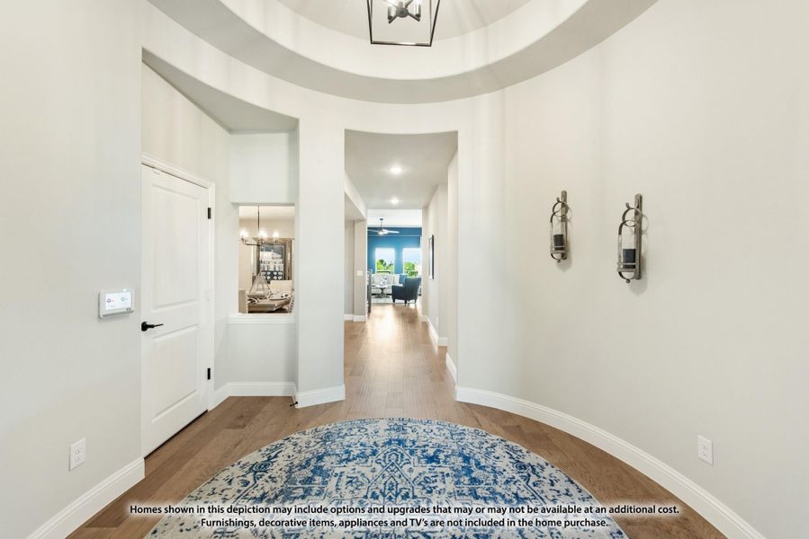 Rounded foyer with tray ceiling, pendant light, hardwood floors, and hallway leading to living areas Rounded foyer with tray ceiling, pendant light, hardwood floors, and hallway leading to living areas