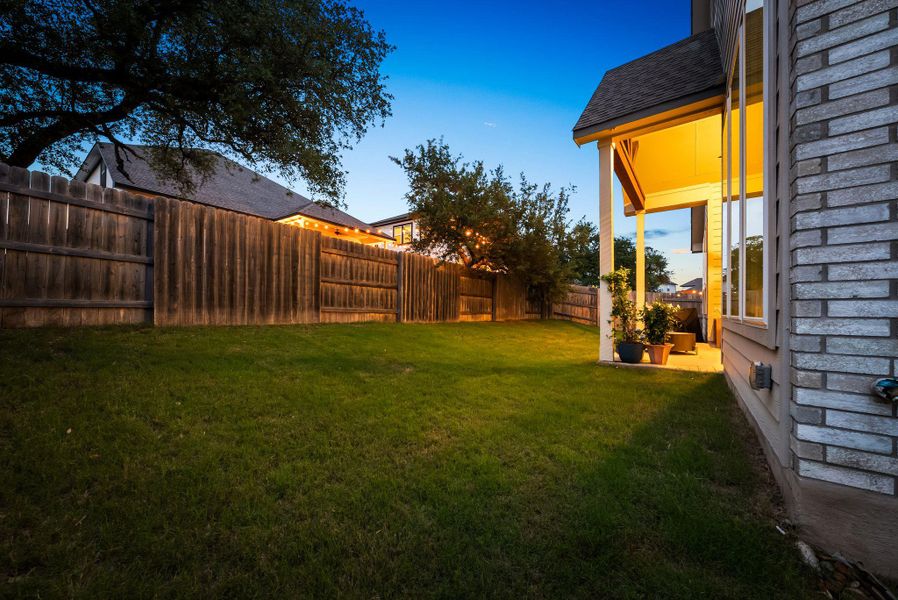 Expansive grassy yard featuring a wood privacy fence, covered patio, and large windows Expansive grassy yard featuring a wood privacy fence, covered patio, and large windows