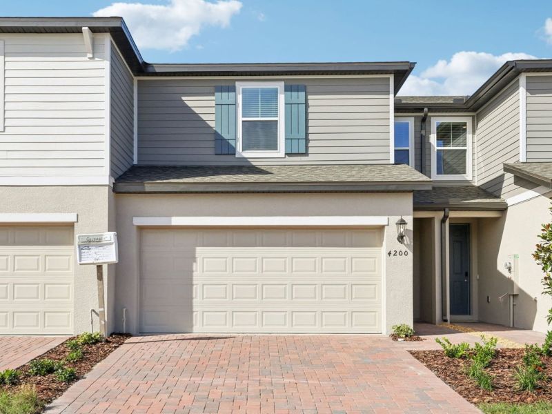 Front exterior of a new home in The Meadow at Crossprairie Townes, St. Cloud, FL, highlighting curb appeal (Image 1). Front exterior of a new home in The Meadow at Crossprairie Townes, St. Cloud, FL, highlighting curb appeal (Image 1).