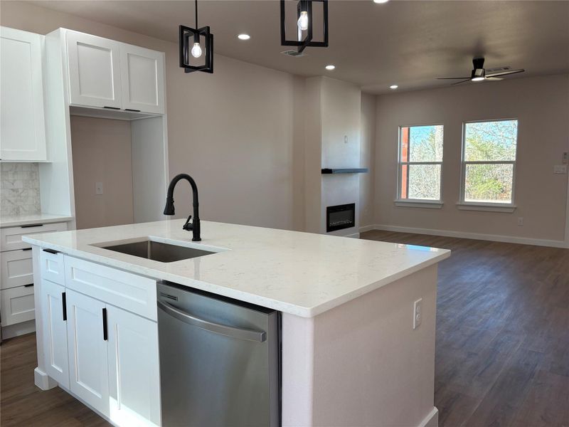 Kitchen featuring dark wood-style flooring, dishwasher, white cabinets, open floor plan, and hanging light fixtures