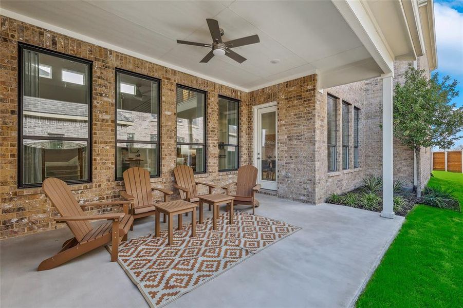 Covered patio featuring a ceiling fan, brick exterior, multiple windows, and a glass-paned door