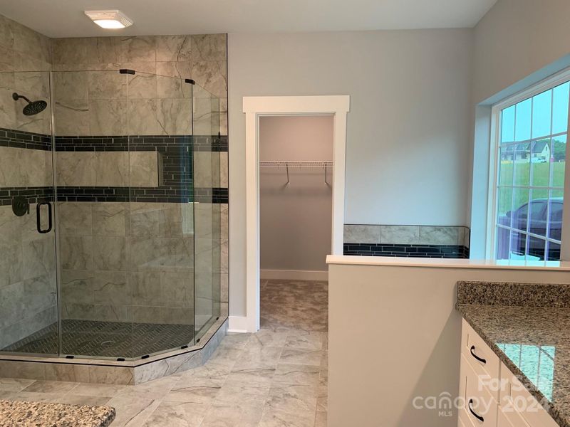 Main bathroom with large frameless shower, garden tub, private commode area, large walk-in closet, and large his & hers separate vanities