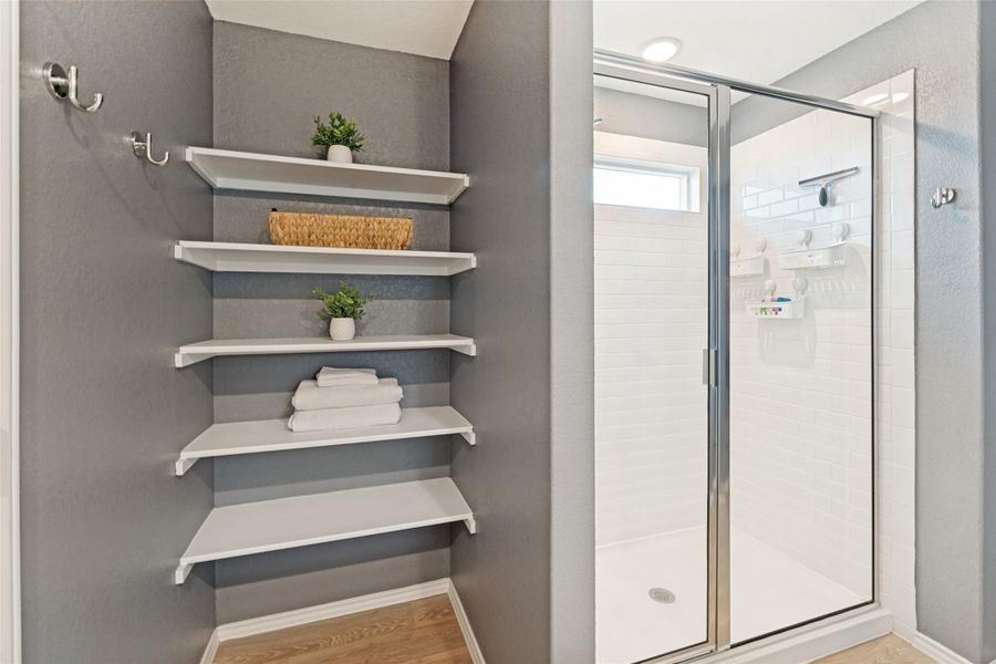 A corner shelving unit offers practical storage alongside a tiled shower enclosure.