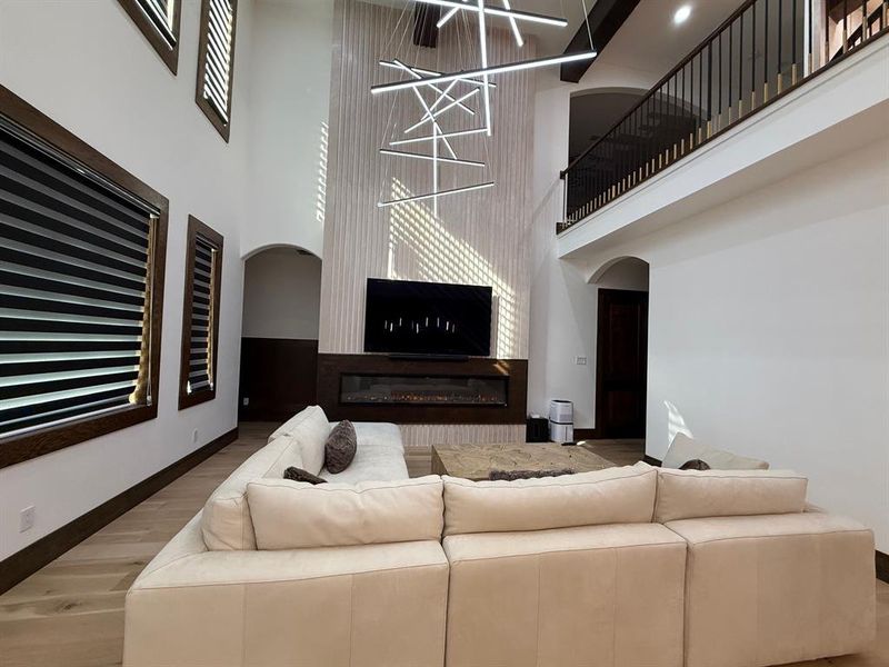 Living room featuring wood finished floors, arched walkways, a high ceiling, and a fireplace