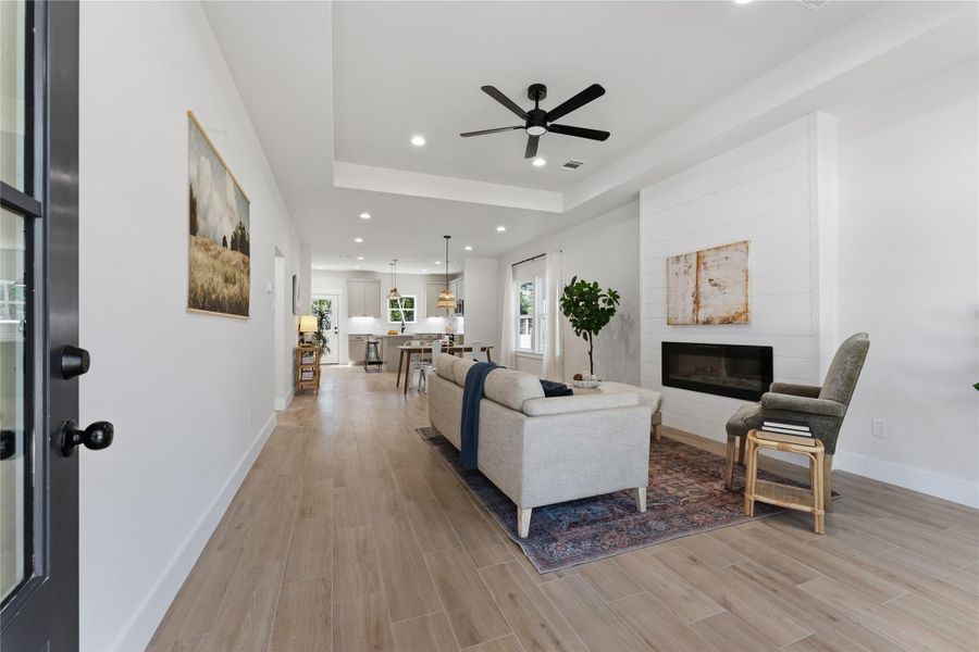Warm, organic finishes create an inviting space open to the kitchen and dining area. An electric fireplace adds a cozy touch, while large windows overlook the peaceful yard where wildlife is often spotted.