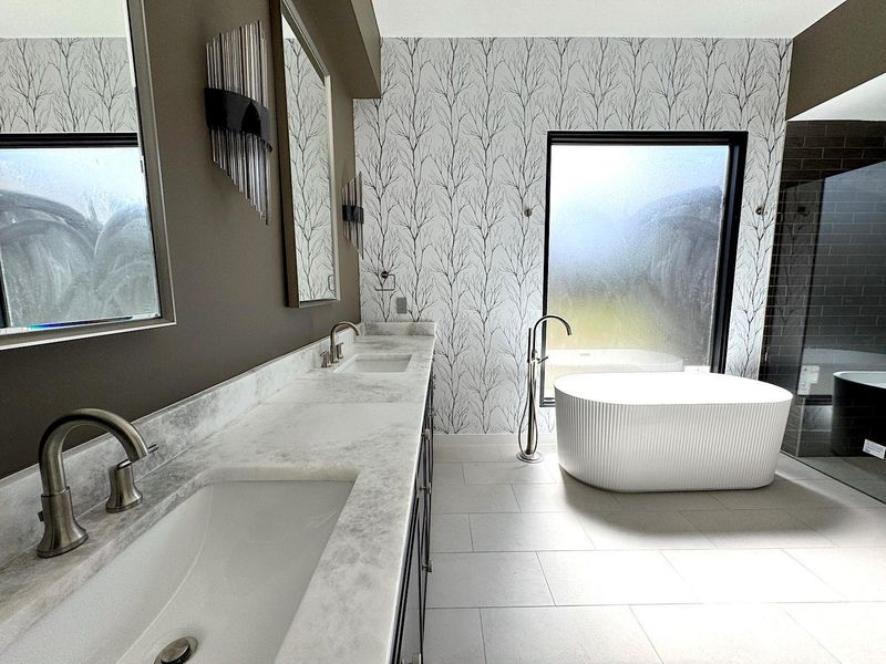 Full bath featuring wallpapered walls, a soaking tub, and a sink