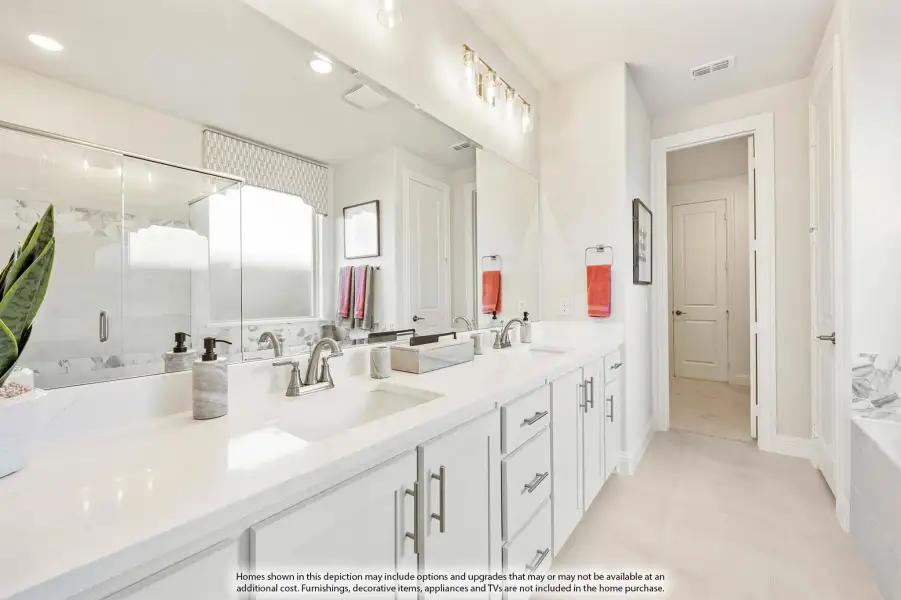 Bright master bathroom with double sink vanity, white cabinets, quartz countertops, and large mirror with glass shower.