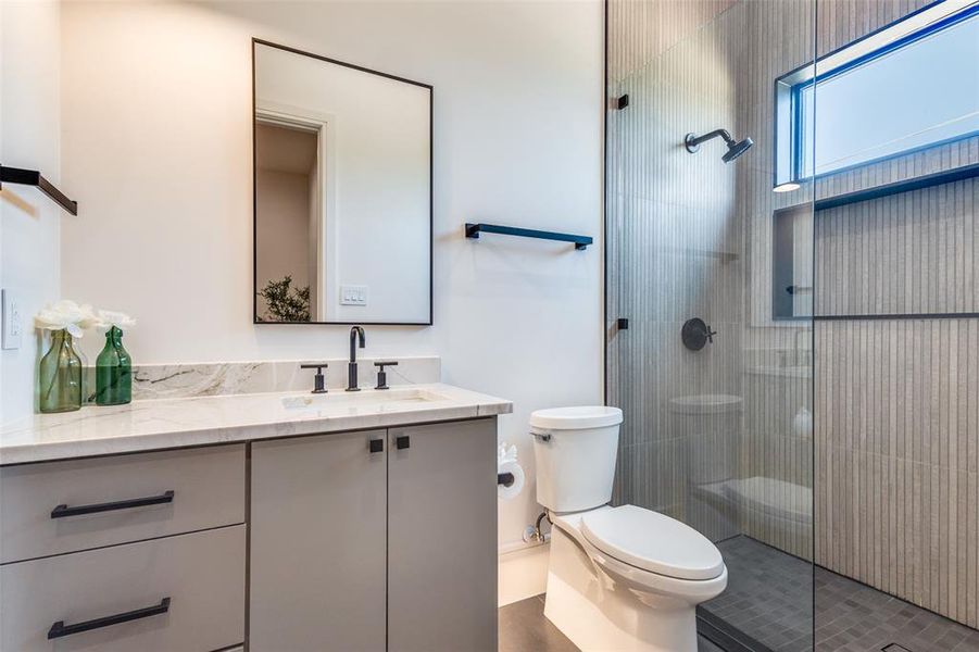 Bathroom featuring vanity with extensive cabinet space, an enclosed shower, toilet, and tile floors