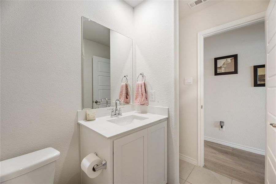 Half bathroom with vanity, a textured wall, and light wood-type flooring