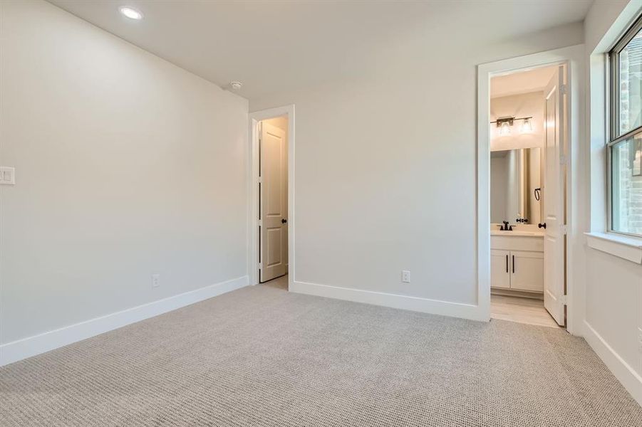 Unfurnished bedroom featuring sink, light carpet, and ensuite bathroom