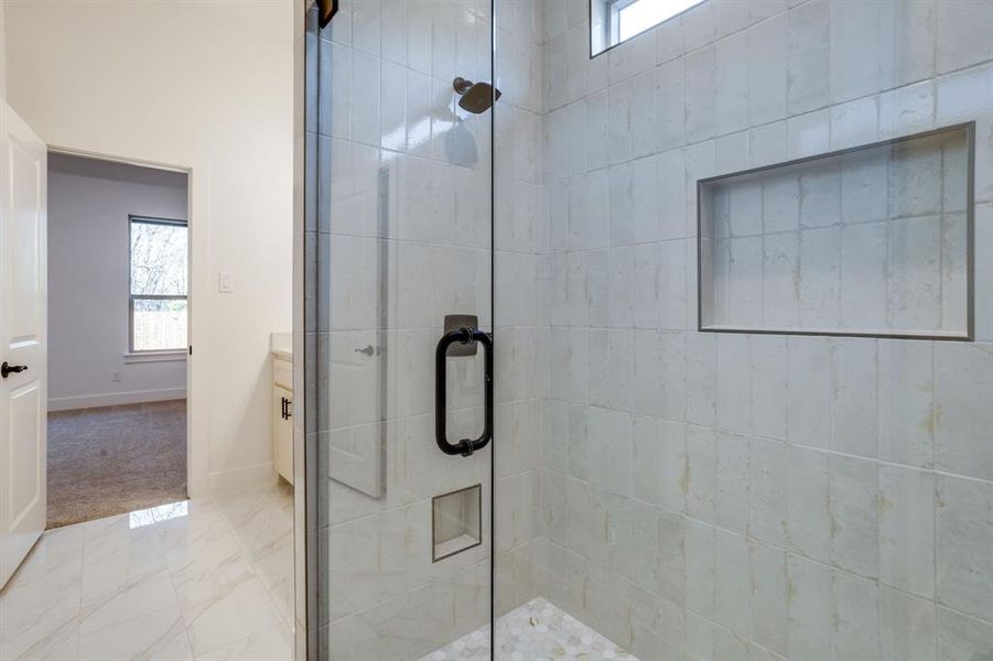 Full bath featuring a stall shower, marble look tiles, and vanity