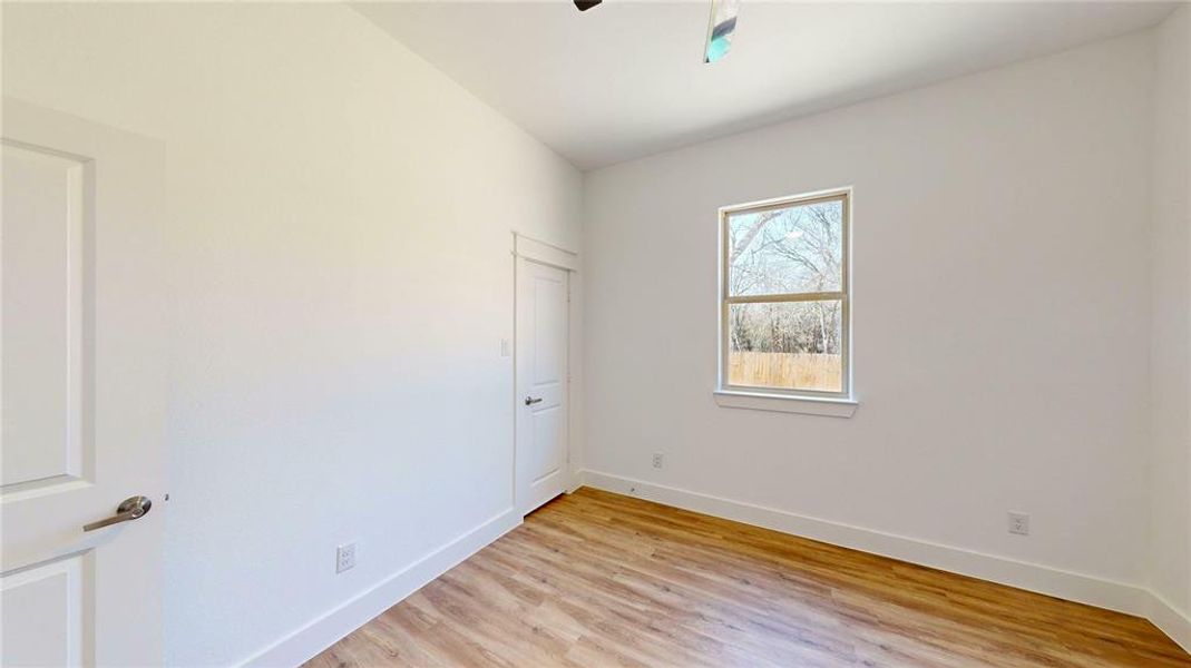 Spare room featuring ceiling fan, light wood-style flooring, and baseboards