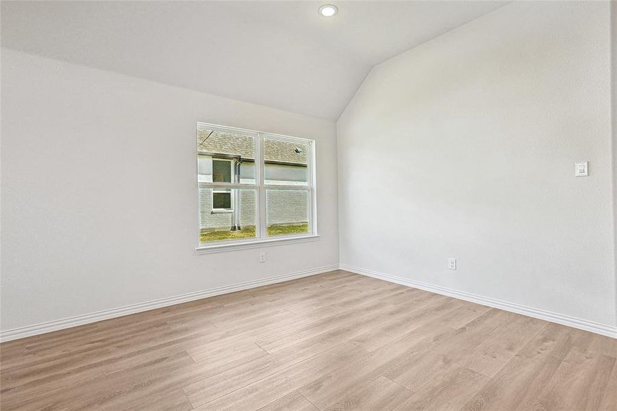 Unfurnished room featuring lofted ceiling and light wood-type flooring