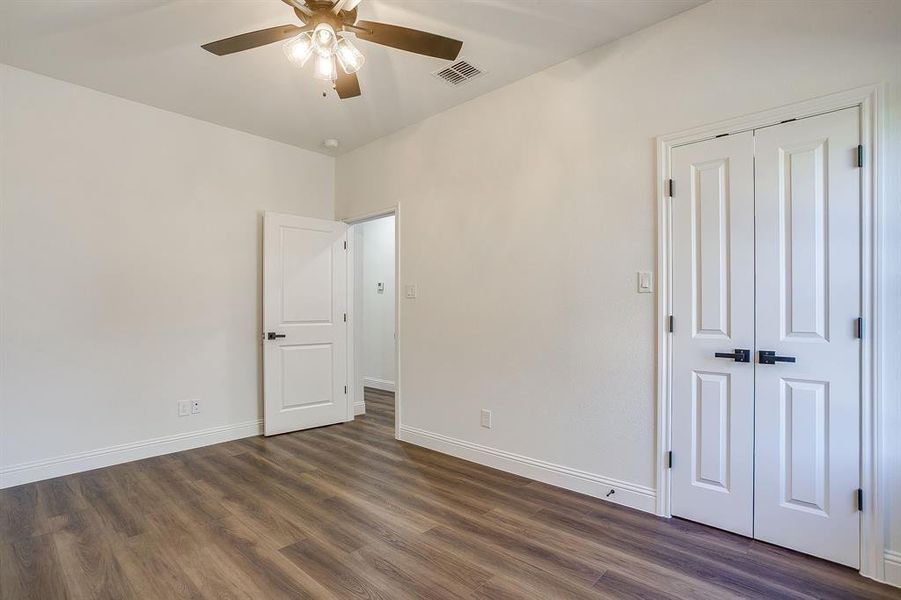 Unfurnished bedroom with dark wood-style floors, a ceiling fan, and a closet