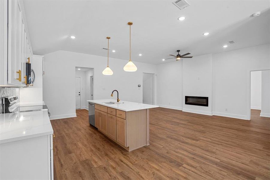 Kitchen with visible vents, a sink, a glass covered fireplace, wood finished floors, and range