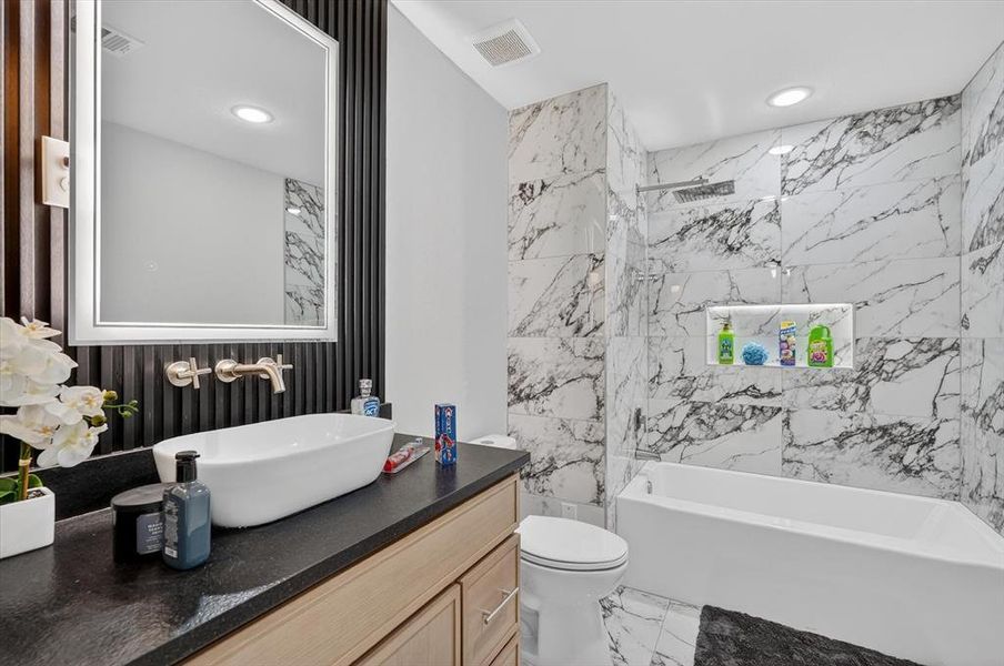 Modern bathroom featuring a freestanding soaking tub with overhead rain shower, a wall-mounted faucet, and a vessel sink