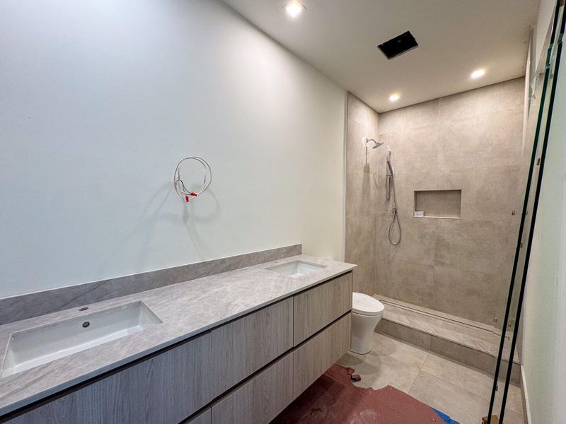 (as of April 8, 2026) a shared bathroom services both guest bedrooms on the second level with a double vanity and framess glass shower, also controlled by Kohler's Anthem Digital Shower Control