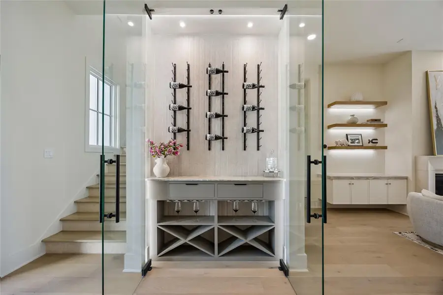 WINE DISPLAY: The glass wine display features custom storage, illuminated shelving, and sleek glass-panel doors, offering both functionality and designer appeal.