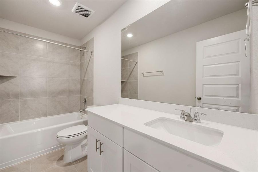 Secondary bath features tile flooring, bath/shower combo with tile surround, bright cabinets, beautiful Quartz countertops, mirror, sleek fixtures and modern finishes.