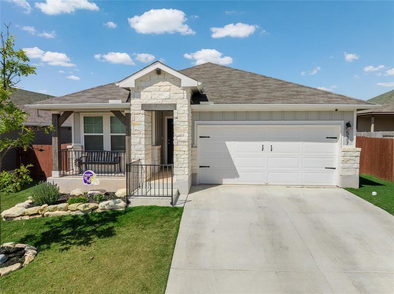 Ranch-style home featuring stone siding, a shingled roof, concrete driveway, and an attached garage
