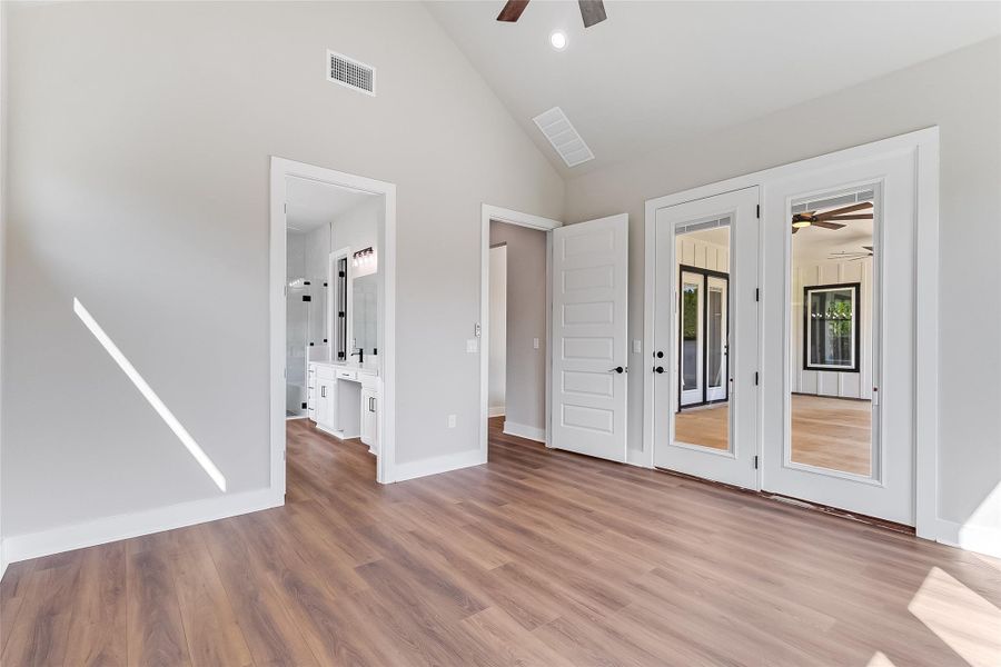 Unfurnished bedroom with lofted ceiling, a ceiling fan, ensuite bath, light wood-type flooring, and recessed lighting