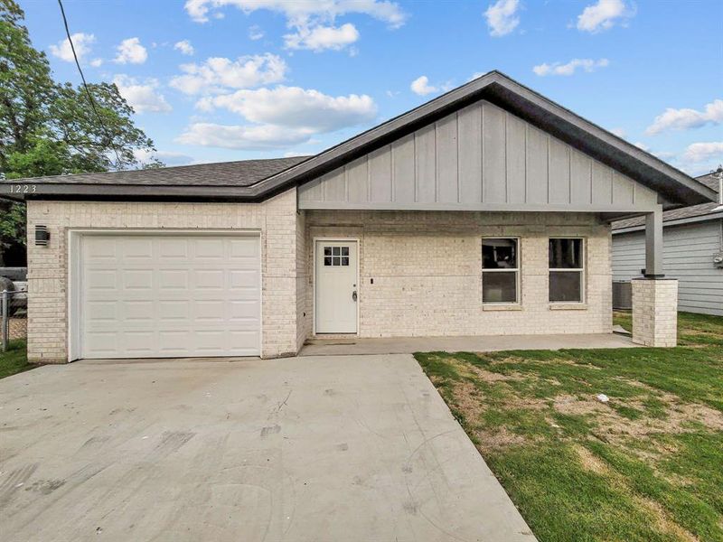 View of front of home featuring driveway, brick siding, board and batten siding, and a garage View of front of home featuring driveway, brick siding, board and batten siding, and a garage