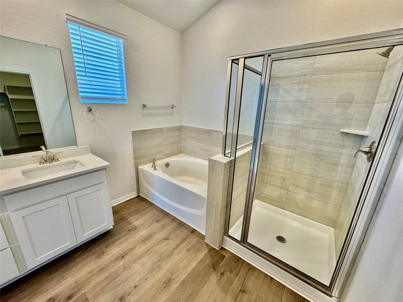Bathroom featuring light wood-style floors, a shower stall, a bath, vanity, and vaulted ceiling