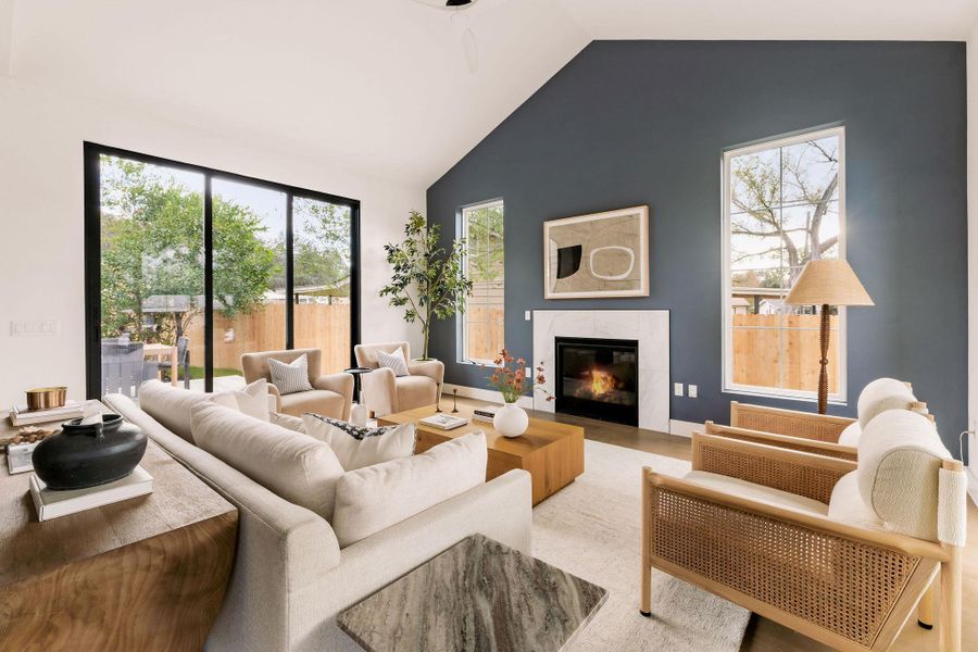 Living area with a glass covered fireplace, lofted ceiling, and plenty of natural light Living area with a glass covered fireplace, lofted ceiling, and plenty of natural light