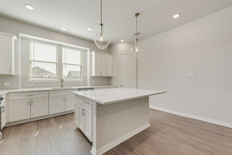 Kitchen featuring white cabinets, light hardwood / wood-style flooring, tasteful backsplash, and a kitchen island