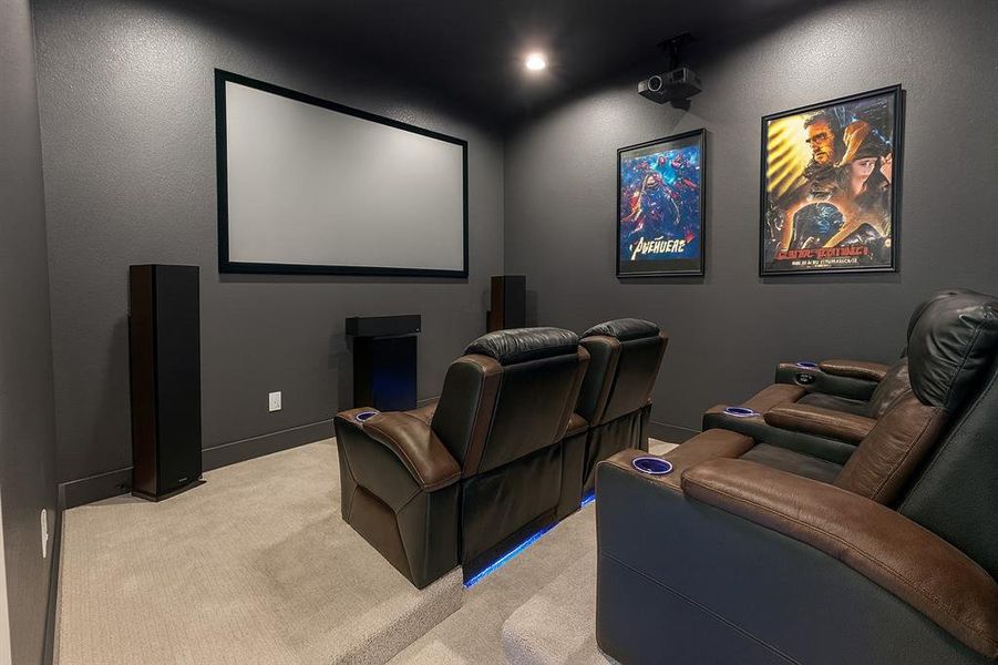 Carpeted home theater room with a textured wall and baseboards