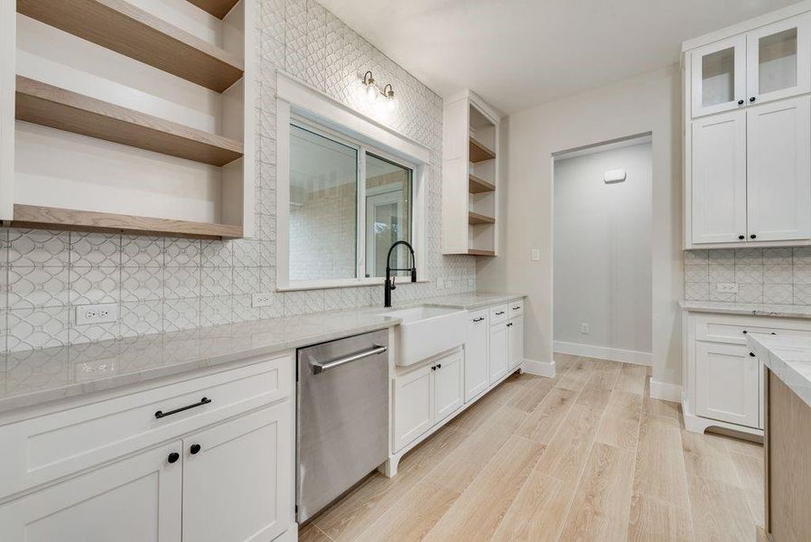 Kitchen featuring white cabinets, light wood-type flooring, stainless steel dishwasher, and sink