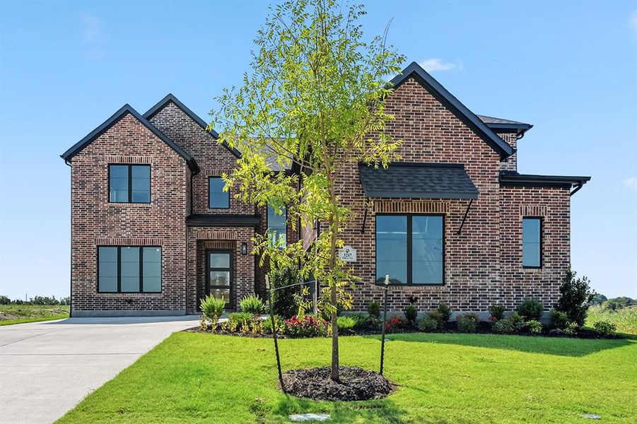 View of front of property with brick siding, driveway, and a front yard