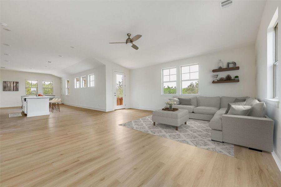 Living area featuring light wood-style floors, a ceiling fan, and vaulted ceiling