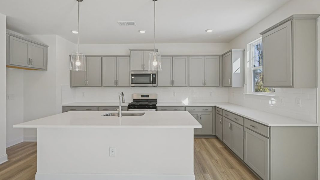 Wagener home plan spacious kitchen with island, tile backsplash, pendant lights, ample counter space and cabinetry