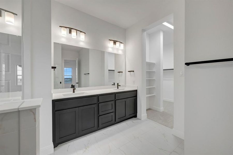 Bathroom with double vanity, a spacious closet, and light marble finish floors