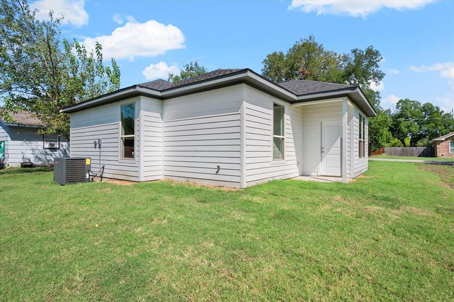 Back of house with cooling unit and a yard